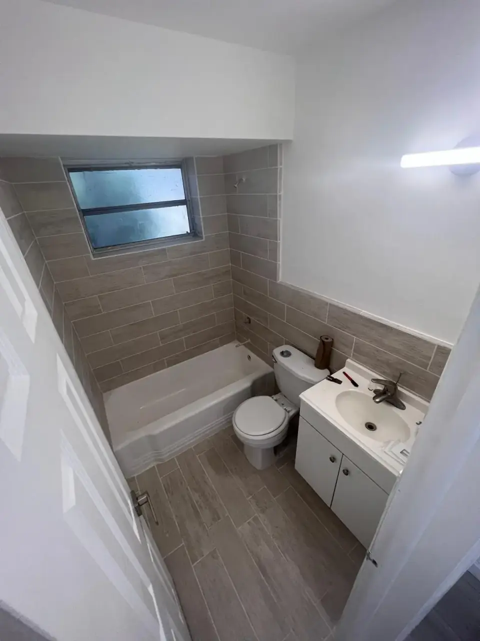 Now: Modern remodeled bathroom with new tiles, tub, and vanity in Miami.