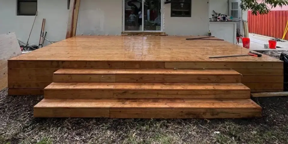 Completed wooden deck installation with steps in backyard area - Miami home improvement