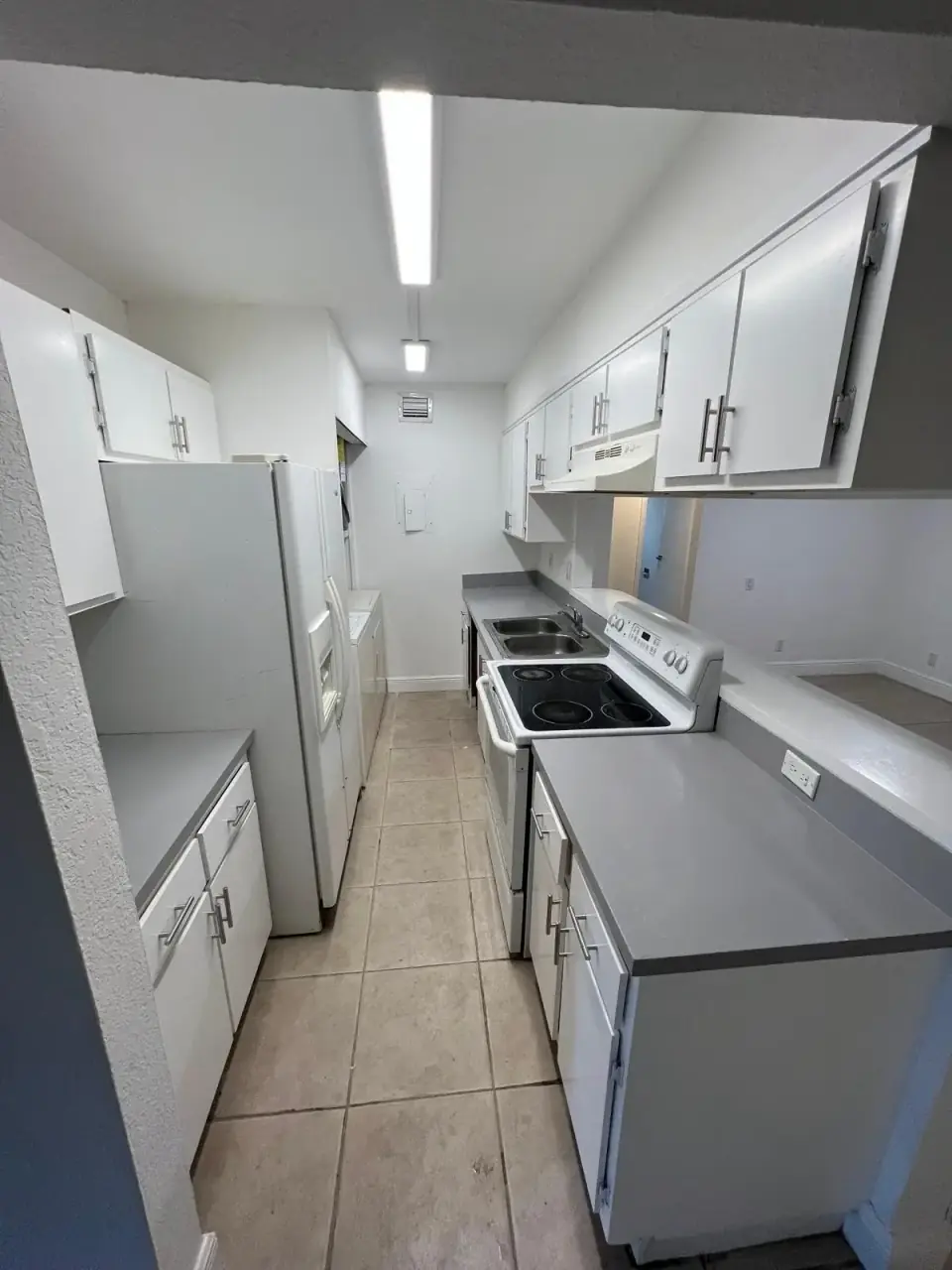 Now: Renovated kitchen with white cabinets, gray countertops, and a clean modern finish in a Miami home