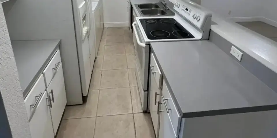 Renovated kitchen with white cabinets, gray countertops, and a clean modern finish in a Miami home