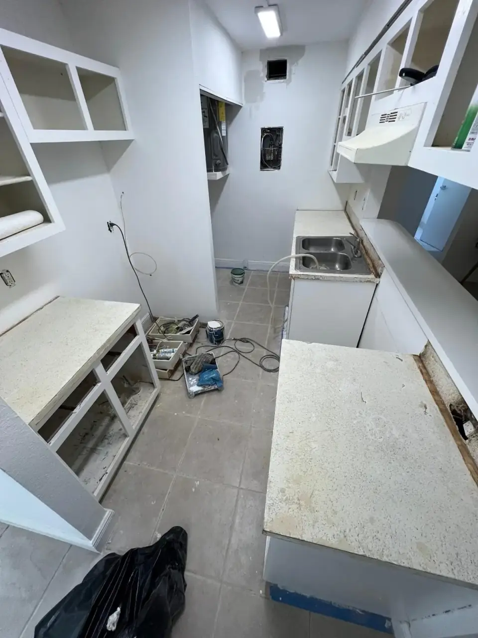 Before: Old kitchen cabinets and countertops being prepped for renovation in a narrow galley-style layout in Miami