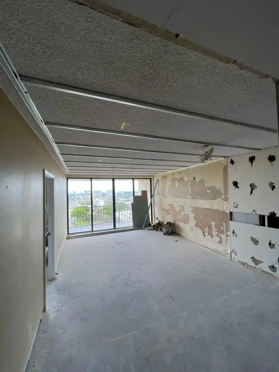Before: Living room before drywall and flooring installation in apartment renovation - Miami