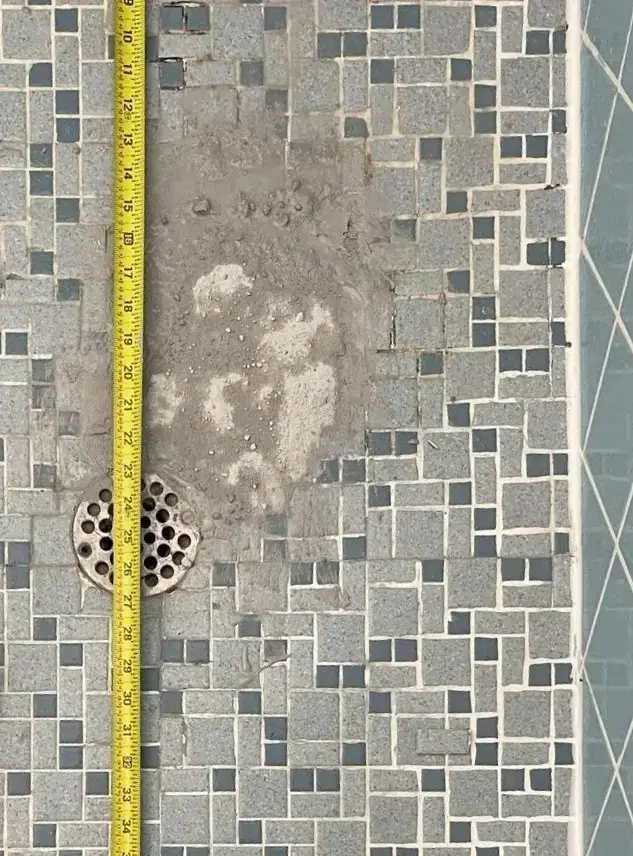 Before: Damaged shower floor before repair with exposed drain and missing tile in Miami