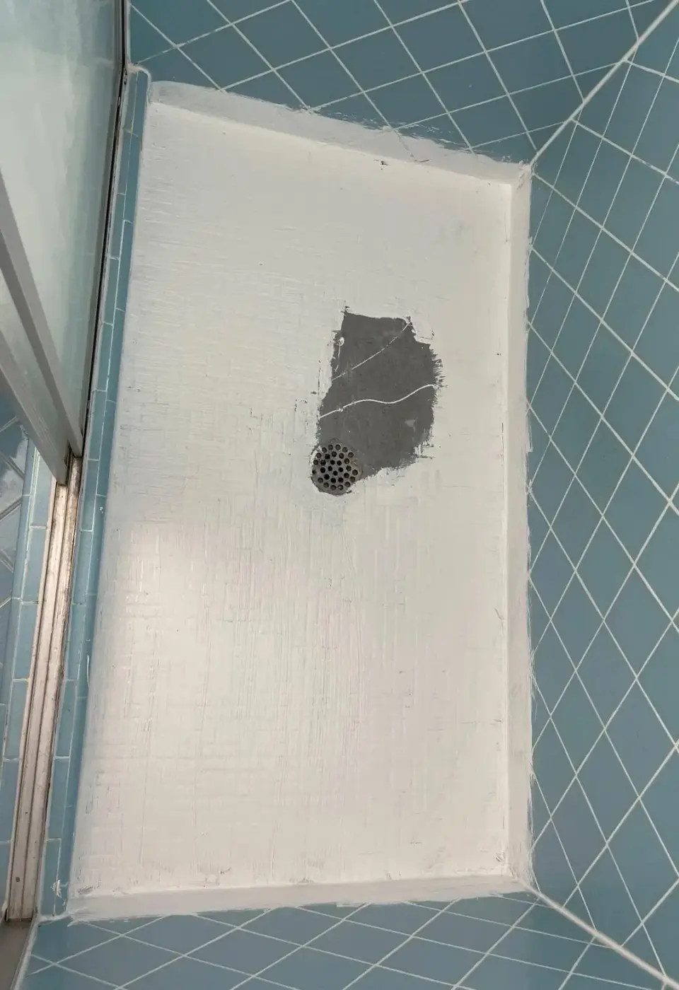 Shower base repair in progress with patching materials applied around the drain in Miami